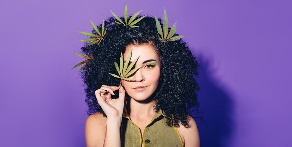 woman holding up cannabis leaves